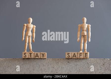 Bild über die Notwendigkeit der Selbstversorgung, in Bezug auf den Ausbruch des Coronavirus, covid-19. Holzfiguren auf Würfeln mit dem Text bleiben sicher. Stockfoto