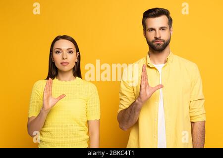 Junges Paar zeigt Geste in Gebärdensprache auf gelbem Hintergrund Stockfoto