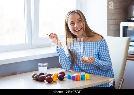 Urlaub, Handarbeit und Kreation Konzept - Happy Young Woman zieht auf Osterei. Stockfoto