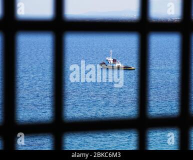 Ein einflügeligtes Schlepper, gesehen durch das Geländer eines Balkons, der vor der Küste in Heraklion, Kreta, Griechenland, verankert ist. Stockfoto