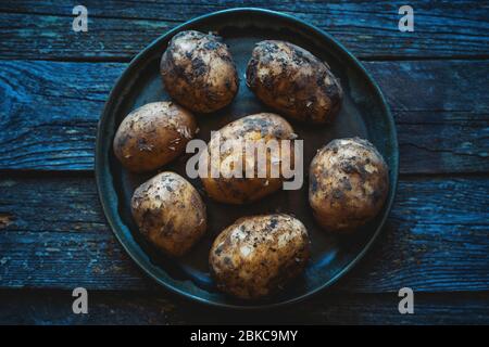 Rohe, schmutzige junge Kartoffeln auf einem Holztisch Stockfoto
