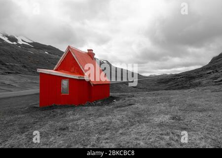 Rote Hütte (isoliert vor schwarz-weißem Hintergrund) auf der Route 1 zwischen Reyðarfjörður und Egilsstaðir im Nordosten Islands. Stockfoto