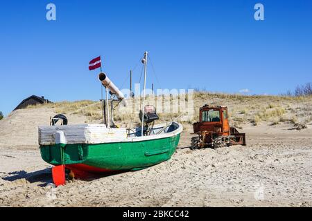 Ein schwerer Bulldozer zieht ein Fischerboot aus dem Meer Stockfoto