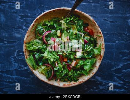 Gesunde hausgemachte Salat von frischem Gemüse mit Zwiebeln, Gurken, Tomaten, Paprika und Blättern mit Sauce und Olivenöl in Schüssel Draufsicht Stockfoto