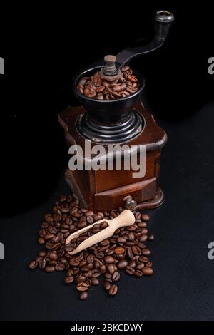 Alte Kaffeemühle auf dem Küchentisch. Ikonisches Zubehör für die Zubereitung von schwarzem Kaffee. Dunkler Hintergrund. Stockfoto