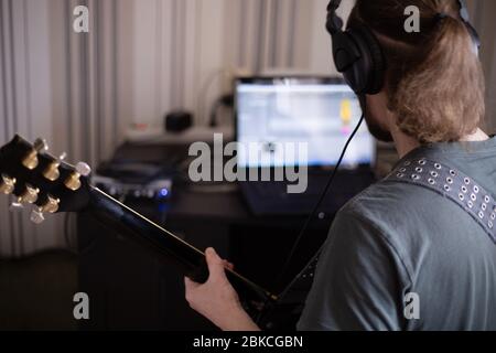 Bärtiger Mann Musiker Musik spielen und komponieren ein Lied mit E-Gitarre Klavier und Laptop-Computer, während im Wohnzimmer sitzen, Corona Virus quar Stockfoto