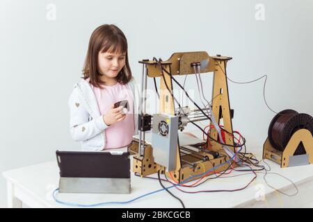 Nettes Mädchen mit 3d-gedruckten Shutter Shades ist beobachten ihre 3d-Drucker, wie es druckt ihr 3d-Modell. Stockfoto