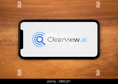 Ein Smartphone mit dem Clearview.ai Logo liegt auf einem einfachen Holztisch (nur zur redaktionellen Verwendung). Stockfoto