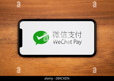 Ein Smartphone mit dem WeChat Pay Logo liegt auf einem einfachen Holztisch (nur für redaktionelle Zwecke). Stockfoto