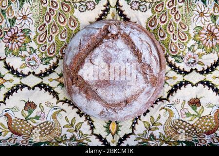 Ein frisch gebackenes Brot aus Roggen und Weizen hausgemachtes Sauerteigbrot von oben auf einem schönen mittelöstlichen Stoffhintergrund UK KATHY DEWITT gesehen Stockfoto