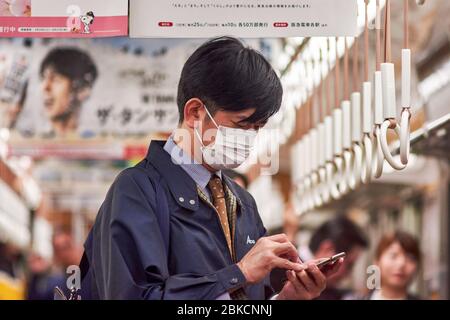 Japanischer Geschäftsmann in einer U-Bahn in Tokio mit einer medizinischen Gesichtsmaske Stockfoto