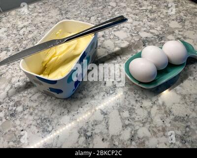 Eier in einem Wallöffel ruhen und eine Wanne Butter mit einem Messer darauf warten gebraten werden. Stockfoto