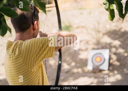 Bogenschießen. Mann, der die Bogenübung mit dem Bogen übt. Sport, Freizeitkonzept. Stockfoto