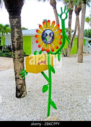 Ein US-Postfach, das von einer Smiley-Face-Blume kunstvoll aus bunt bemaltem Metall gehalten wird, zieht das Auge der Menschen auf diesem bunten Haus auf Casey Key in Sarasota County entlang der Golfküste von Florida, USA, vorbei. Es ist das kreative Werk von Floridian Scott Gerber, der 2010 seine erste lächelnde Stabfigur aus Aluminiumschrott fertigte. Seitdem hat seine Tube Dude Firma Tausende von skurrilen Skulpturen in verschiedenen Designs an Kunden weltweit verkauft. Stockfoto
