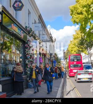 Londoner und Touristen kaufen auf der Pembridge Rd, Notting Hill, London England ein. Doppeldeckerbus fährt auf der Straße. Stockfoto