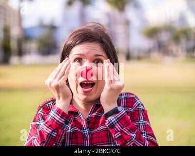 Überraschte junge Mädchen mit einer Clownsnase. Witz, Humor und lustiges Porträtkonzept. April Narren Tag. Stockfoto