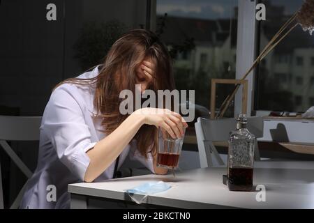 Ärztin ist depressiv. Einsame weibliche Trinker Alkoholiker leiden unter Alkoholsucht mit Problem, Alkoholismus Konzept. Die Folgen eines Stockfoto