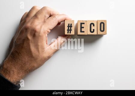 ' Eco ' Text aus Holzwürfel auf weißem Hintergrund mit Menschenhand gemacht. Stockfoto