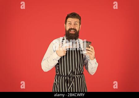 Frischer Kaffee hier. männliche Kaffee trinken. bärtiger Mann halten Sie Kaffee nehmen. brutale Kellner im Cafe. reifer Mann roten Hintergrund. Qualifizierte Diener. Barista hipster Koch Schürze. Elegante zuversichtlich Barkeeper. Stockfoto