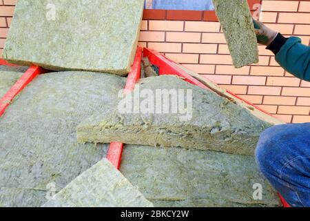 Der Arbeiter dämmelt das Dach mit der Mineralwolle.2020 Stockfoto