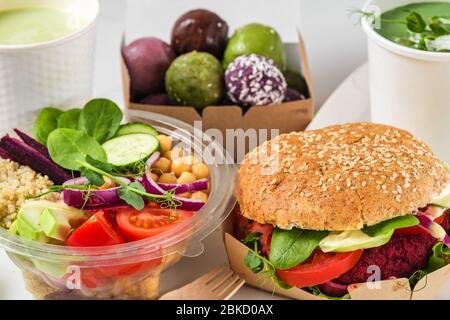 Gesunde vegane Lebensmittel liefern. Buddha Schüssel Salat, Burger, Suppe, Dessert und Matcha Latte in Kisten und Tassen verpackt. Restaurant-Menü zum Mitnehmen Stockfoto