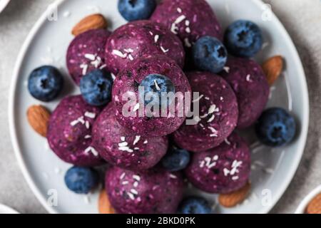 Keine backen Heidelbeere und acai Energie Bissen oder Kugeln, mit natürlichen Zutaten wie Nüsse, Kokosflocken und Datteln zubereitet. Top view. Gesund vegan f Stockfoto