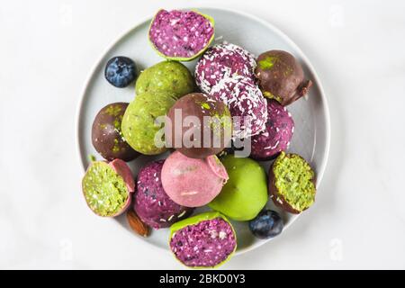 Leckere vegane Desserts. Rohe Kekse aus Bio-Nüssen, Datteln, Matcha, acai und Beeren in Schokoladenglasur. Draufsicht. Gesunde Snacks Stockfoto