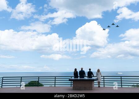 Am 6. Juni 2019 beobachteten Präsident Trump und First Lady Melania Trump zusammen mit dem französischen Präsidenten Emmanuel Macron und seiner Frau Brigitte Macron einen Überflug von F-15-Flugzeugen auf dem amerikanischen Friedhof in der Normandie, anlässlich des 75. Jahrestages des D-Day. Stockfoto