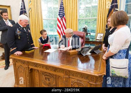 Präsident Donald J. Trump schreibt eine Ausrede aus der Schulnote für den Empfänger der Ehrenmedaille, den der ehemalige US-Armeekaptitel Gary M. Rose Enkel, Christian, während eines Familienbesuchs im Oval Room des Weißen Hauses in Washington, D.C. am 23. Oktober 2017, 2017. November   links hatte: Monat der nationalen Veteranen und Militärfamilien Stockfoto