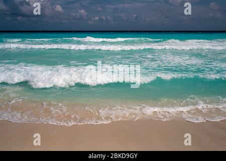 Türkisfarbene Meereswellen, die auf den Sandstrand stürzen Stockfoto