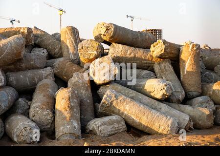 Großer Stapel von Betonpfählen auf der Baustelle, Turmdrehkrane im Hintergrund. Stockfoto