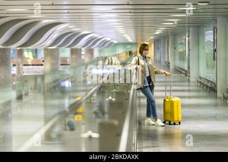 Frau mit Gepäck am leerstehenden Flughafenterminal aufgrund von Einschränkungen für Reisen mit Coronavirus Pandemic/Covid-19-Ausbruch. Flugstornierung. Reiserindu Stockfoto