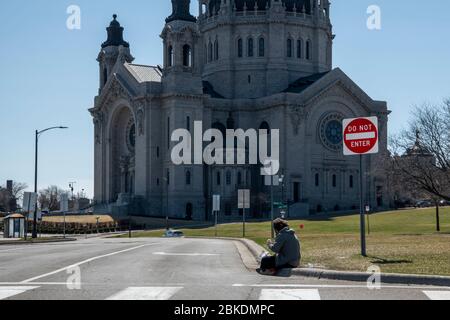 St. Paul Ein Obdachloser, der auf einem Bordstein sitzt, wartet auf ein Handout auf einer leeren Straße wegen der Coronavirus-Pandemie. Stockfoto