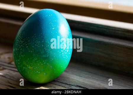 Leuchtend gefärbtes blaues Ei für ostern Konzept auf alten Holzfenster platziert Stockfoto