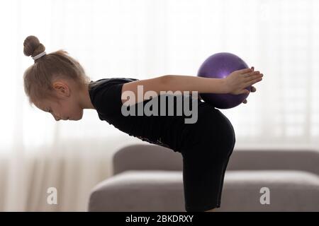 Flexible niedliche kleine Mädchen Kind Turner tun akrobatische Übung mit Ball. Sport, Training, Fitness, aktives Lifestyle-Konzept Stockfoto