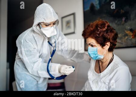 Hausarzt / Krankenschwester Hören der Lungen der älteren Patienten mit einem Stethoskop.COVID-19 Patienten Selbstisolierung Untersuchung.Coronavirus Frontlinie mich Stockfoto