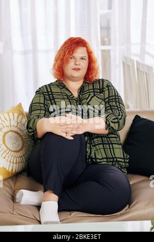 Porträt einer jungen übergewichtigen Frau, die zu Hause auf dem Sofa ruht Stockfoto