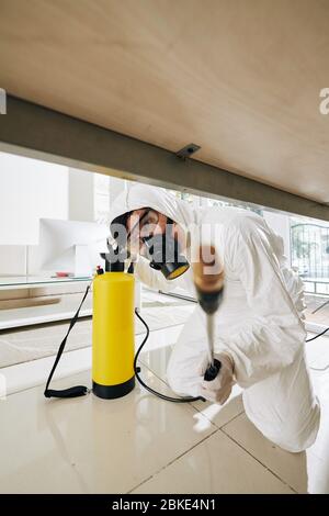 Reinigungsdienstmitarbeiter in Gefahrgutanzug sprühen jede Ecke im Haus mit Desinfektionsmittel Stockfoto