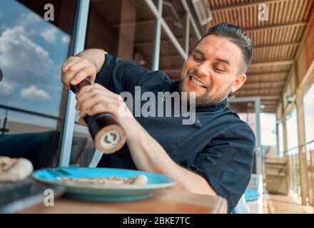 Ein bärtiger Mann schält ein Gericht Stockfoto