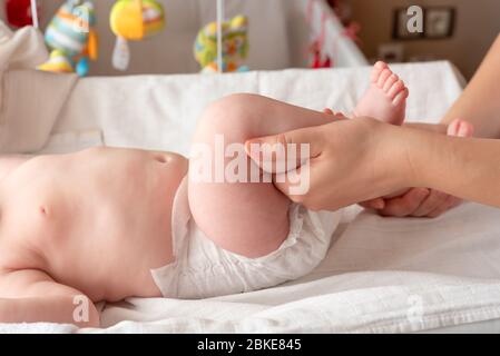 Gymnastik Baby. Frau macht Übungen mit Kind für seine Entwicklung. Massieren Sie ein kleines neugeborenes Baby, indem Sie Übungen an den Beinen machen. Baby Massage, Mutter Stockfoto