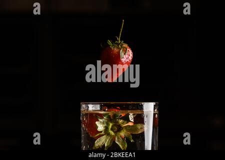 Erdbeere fällt in ein Glas Wasser Stockfoto