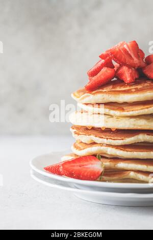 Pfannkuchen-Stapel mit Erdbeeren und Honig auf einem weißen Teller. Stockfoto