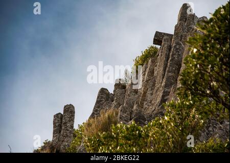 Die Orgelpfeifen, einzigartige Basaltsäulen Mt Cargill, Dunedin, Neuseeland. Vertikale Säulen aus vulkanischem Gestein stand vor einem Blauen, bewölkter Himmel Hintergrund Stockfoto