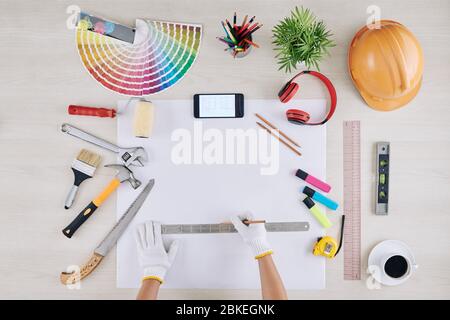 Conscturction Ingenieur Zeichnung Haus Blaupause auf weißem Blatt mit Werkzeugen, Gadgets, Hardhat und Tasse Kaffee um Stockfoto