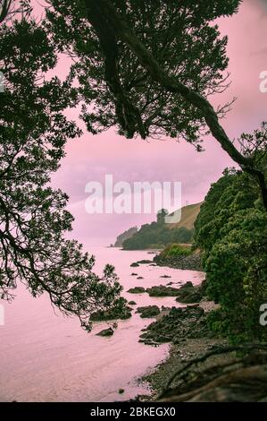 Blick auf die Küste an einem bewölkten Tag in der Nähe von Whakatane, Neuseeland. Regentage an der Westküste der Coromandel Peninsula, gespalten rosa/grün Stockfoto