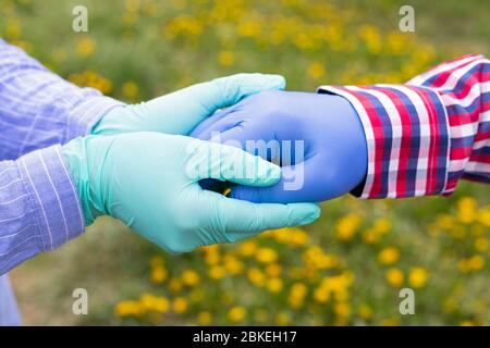 Hände halten - Handschuhe tragen wegen der COVID-19-Pandemie - Pflegekraft, die die Hände älterer Patienten hält Stockfoto