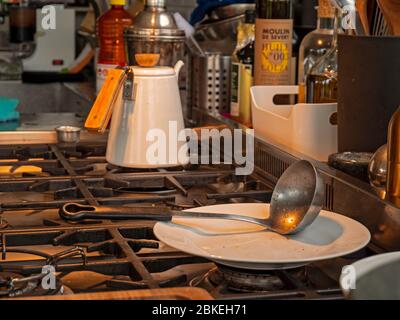 Ein Heißwasserkrug in einer rustikalen Küche. Die Jut sitzt auf dem Ofen mit anderen Küchenutensilien um ihn herum in der modernen und rustikalen Küche. Stockfoto