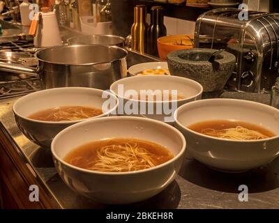 Nahaufnahme von Schalen von Ramen in einer Küche. Die Schalen mit Dashi-Brühe und Nudeln sind eine traditionelle japanische Mahlzeit. Stockfoto