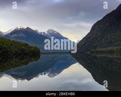 Lake Gunn, Fiordland, Neuseeland. Malerische Landschaft, schneebedeckte Berge spiegeln sich in einem klaren See. Stockfoto