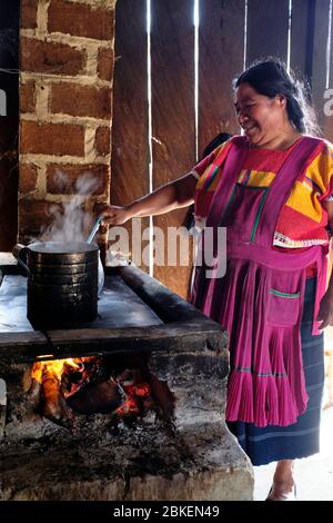 Maya-Frau in bunten einheimischen Kleidung Kochen in einem einfachen Holzofen in ihrem Haus in Amatenango del Valle gekleidet. Stockfoto